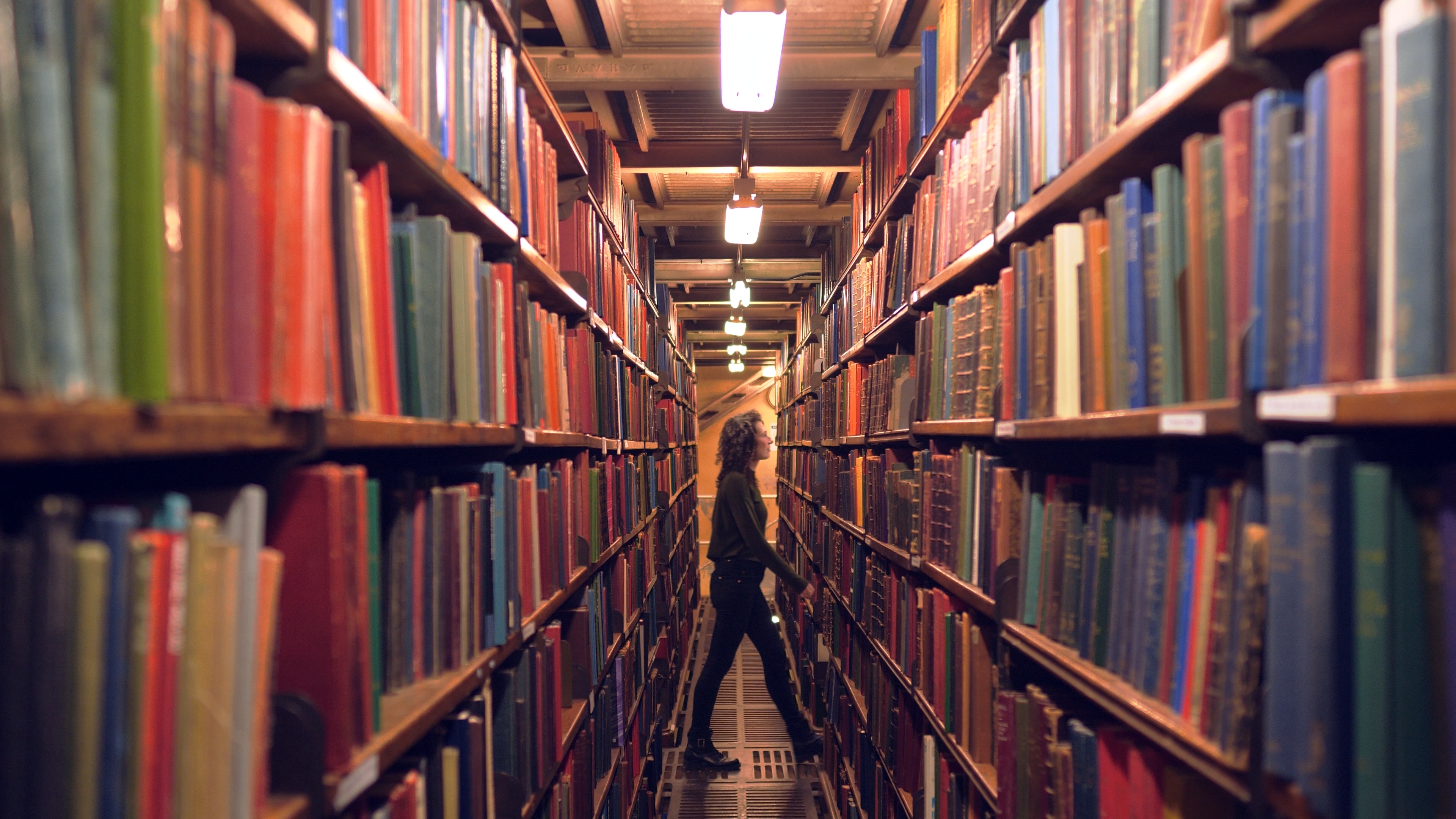 Woman walking through stacks in the library