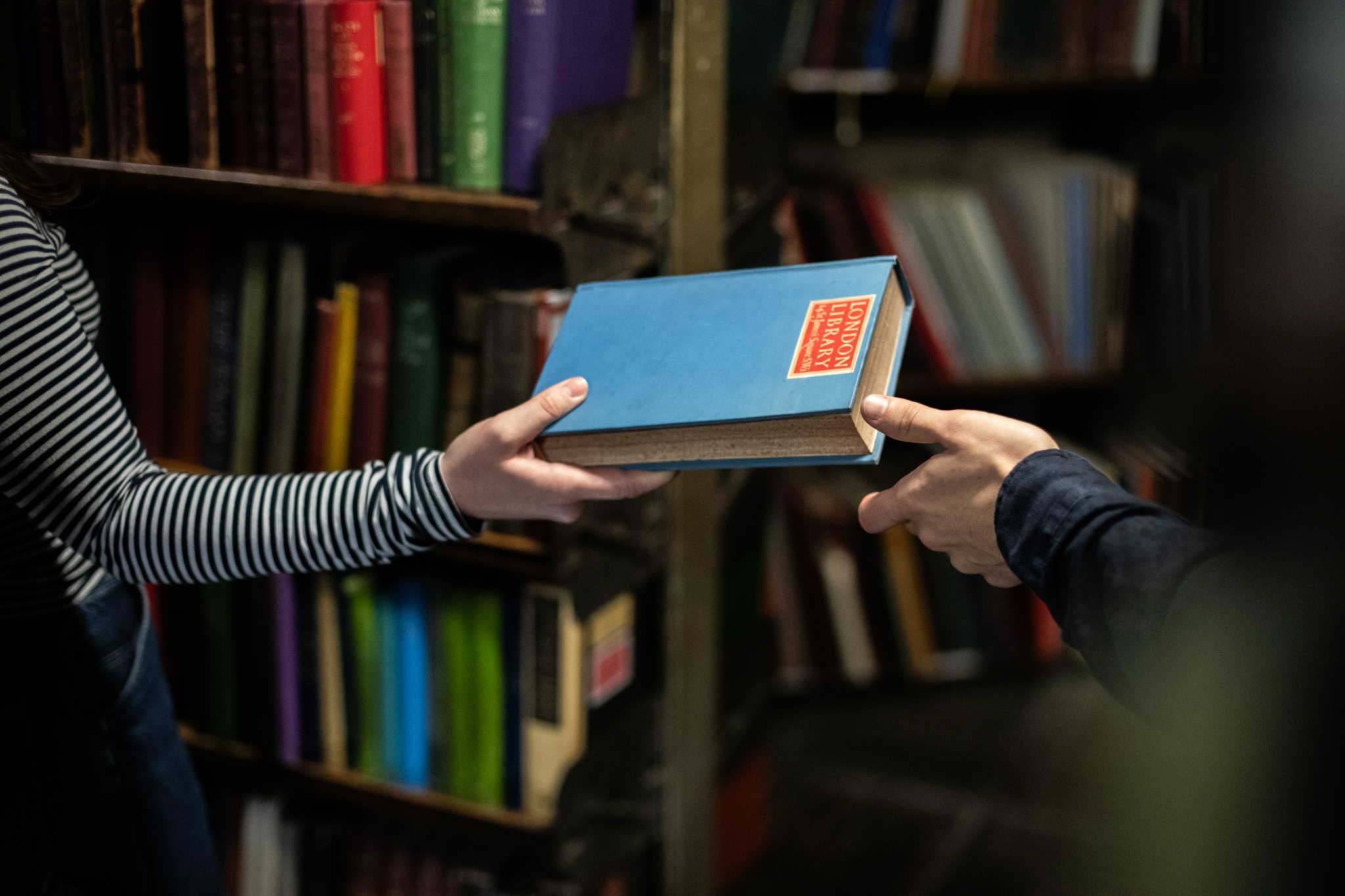 One person handing a book to another person
