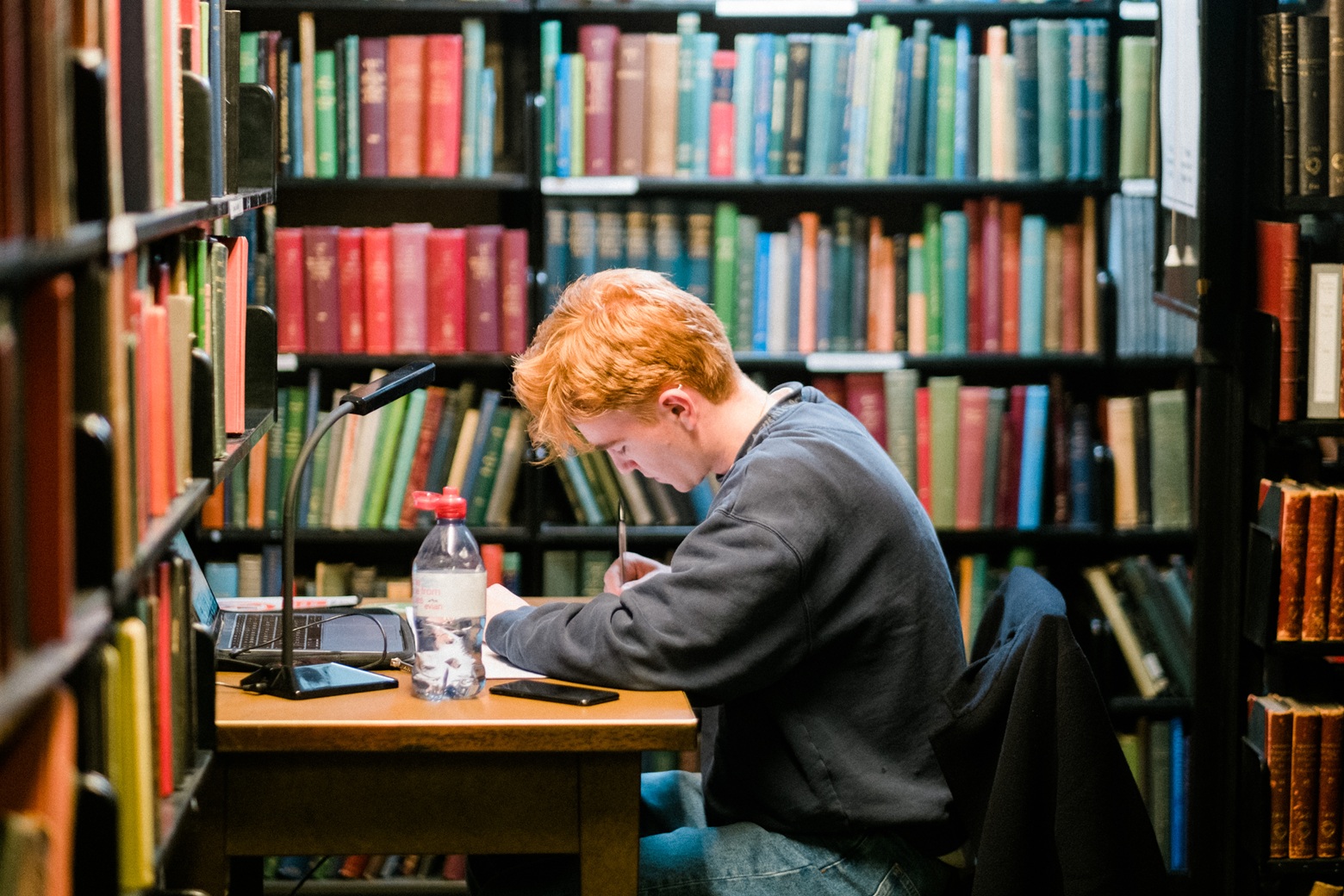 Young member studying at a Library desk in the stacks