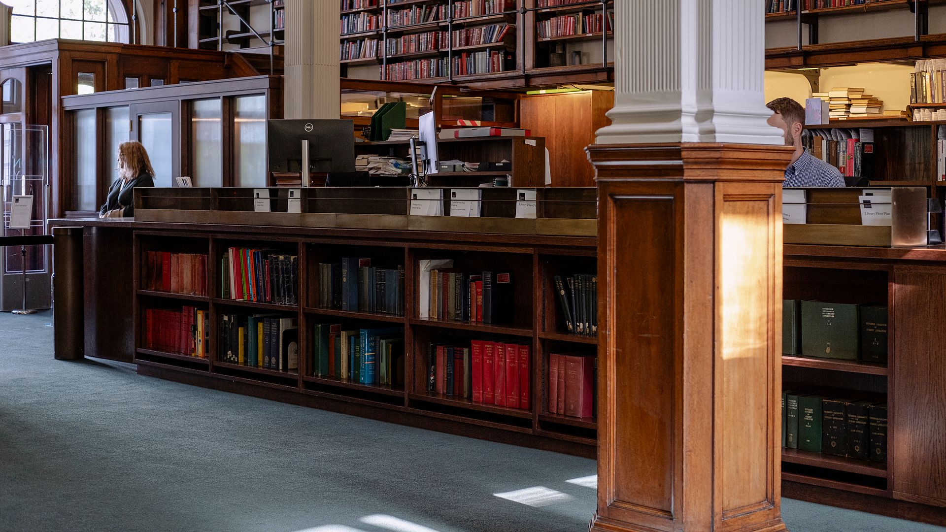 The reading room interior with a wooden column, low bookcases and tall shelves beyond.