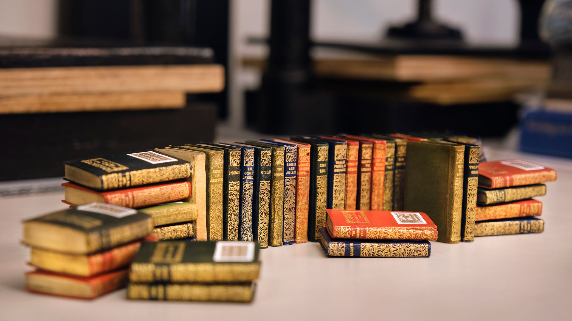 Rows of gilt-decorated miniature books arranged on a bindery workbench.