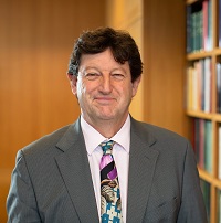 Portrait of Patrick, a white man with dark hair in a grey suit and graphic tie.