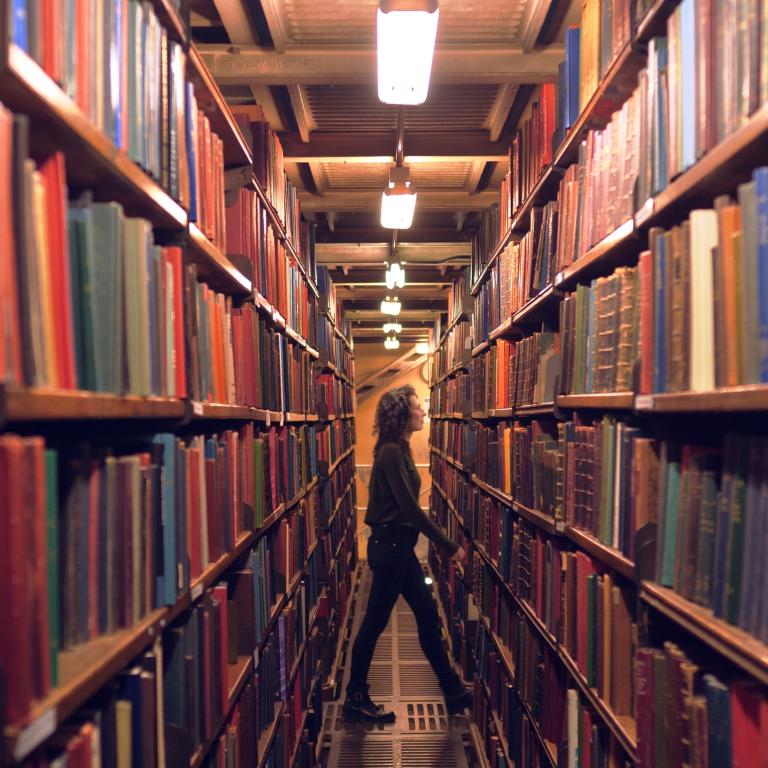 Woman walking through stacks in the library