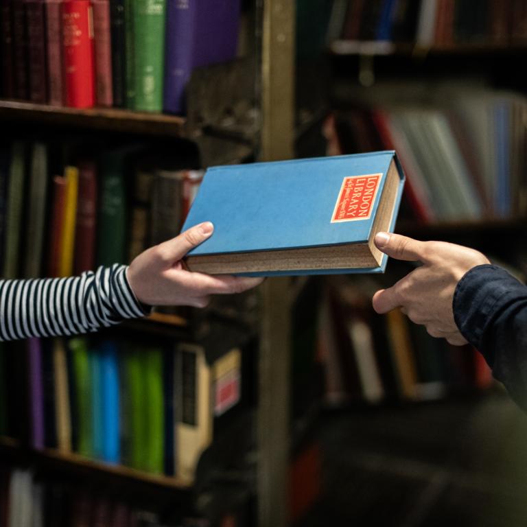 One person handing a book to another person