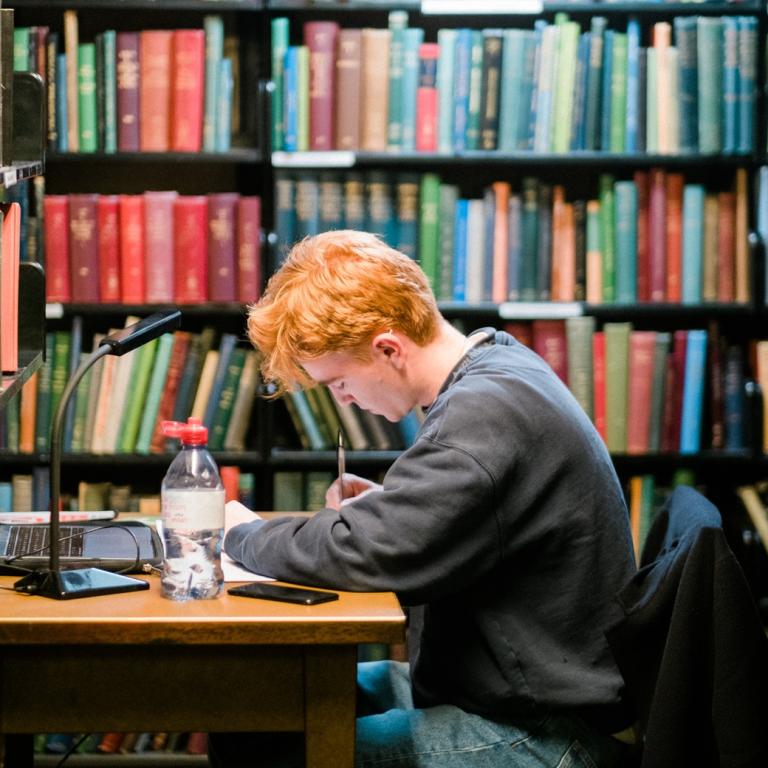 Young member studying at a Library desk in the stacks