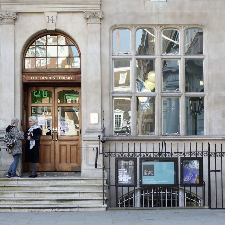 The London Library's stone entrance at number 14, two visitors at the wooden doors.