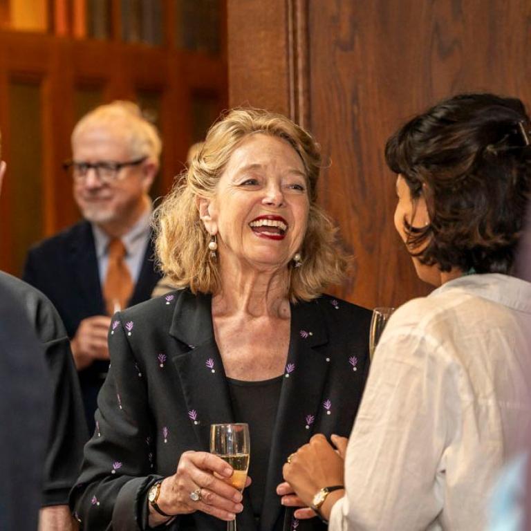 A guest laughs in conversation over a glass of champagne at the reception.
