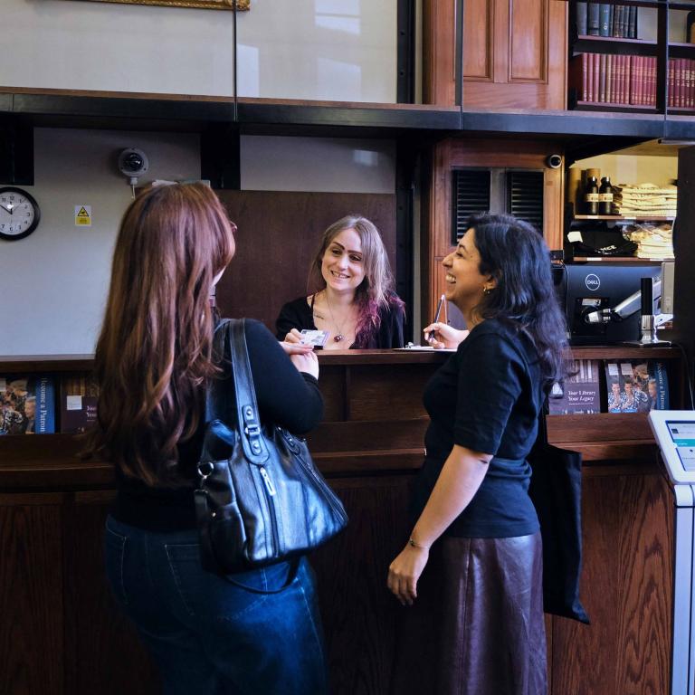 A member is served at the issue desk by two members of staff.