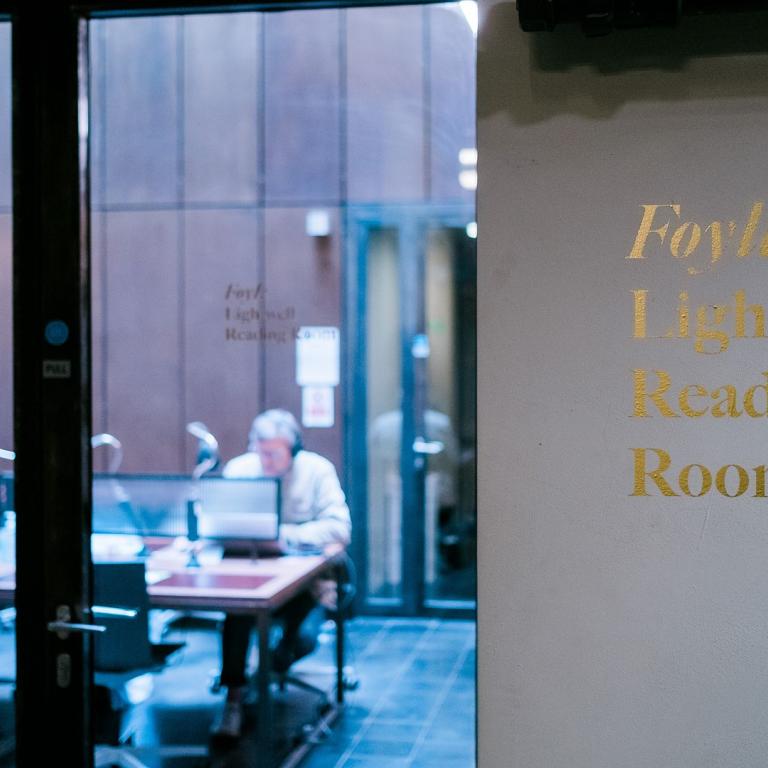 Gold lettering reading "Foyle Lightwell Reading Room" beside a glazed door, a reader at a desk visible inside.