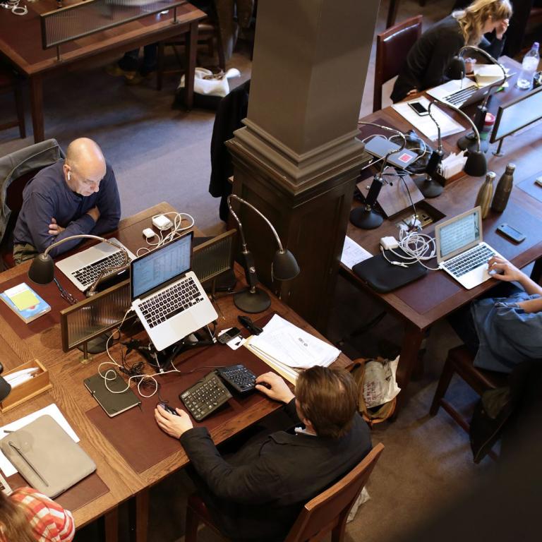 Members working at laptops across the reading room desks, seen from the gallery above.