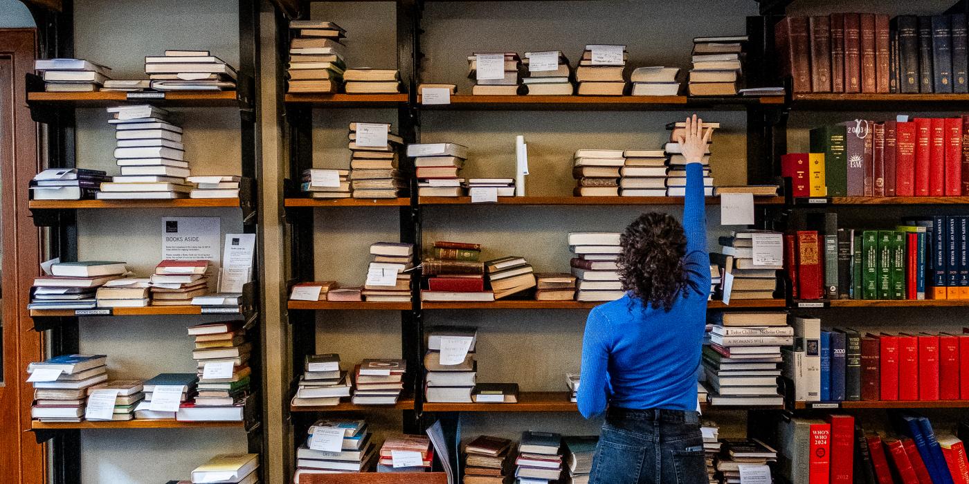 Woman reaching for a book on a shelf 