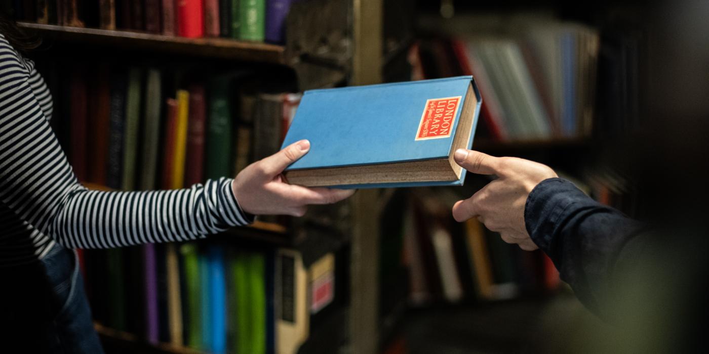 One person handing a book to another person