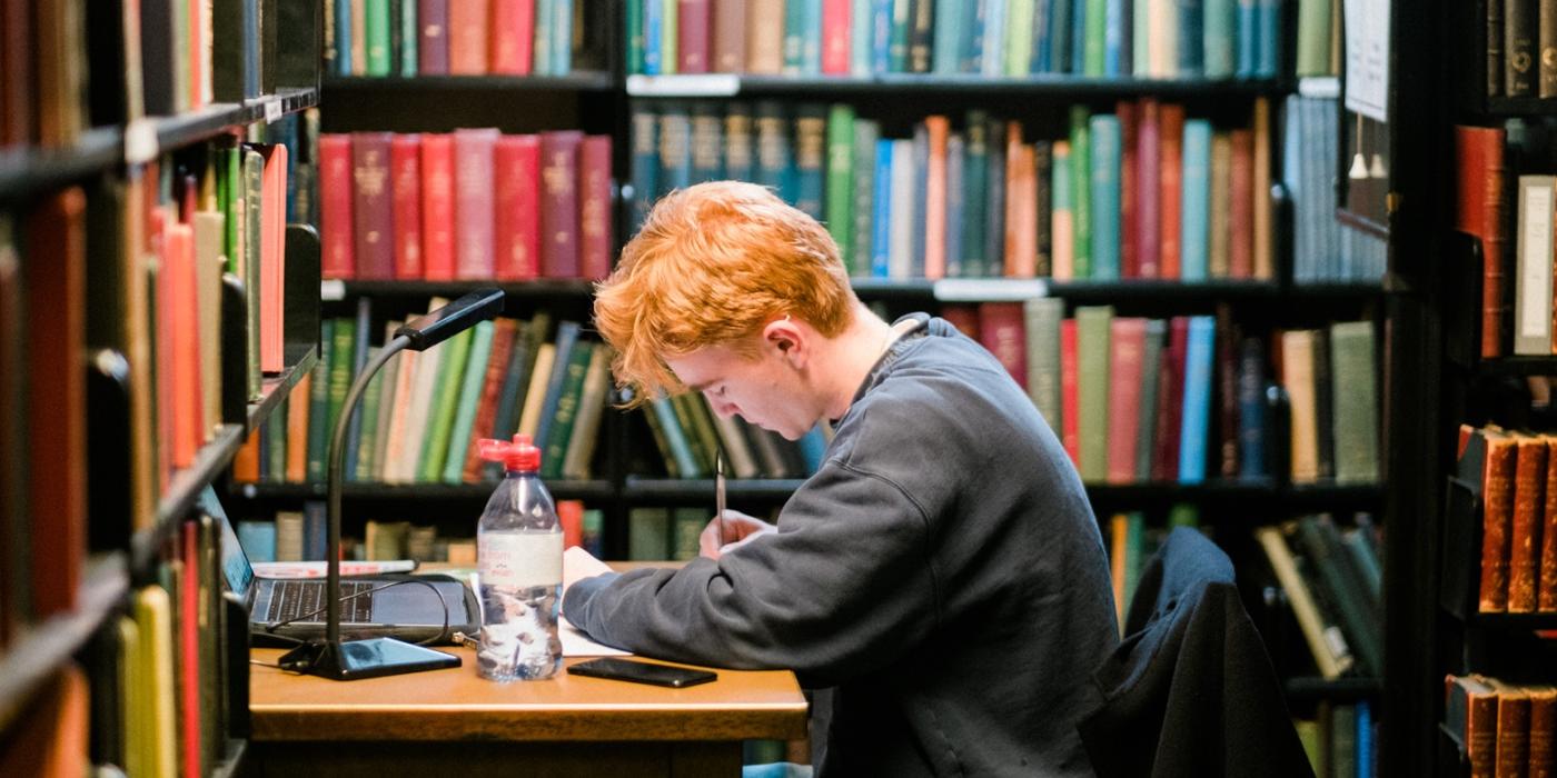 Young member studying at a Library desk in the stacks