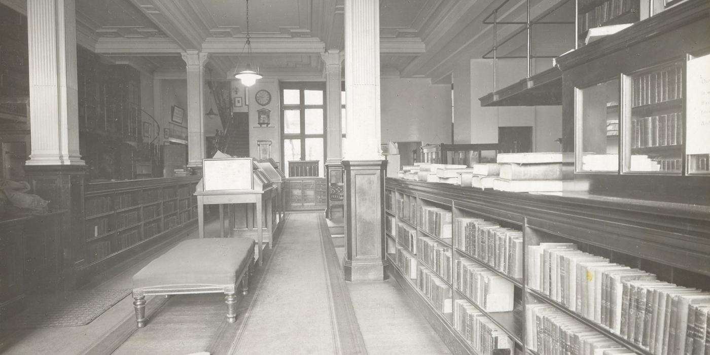 A long book-lined gallery with a day bed and reading stand, photographed in 1935.