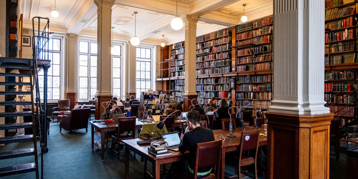 The Reading Room looking towards tall windows, members at desks under globe lights.