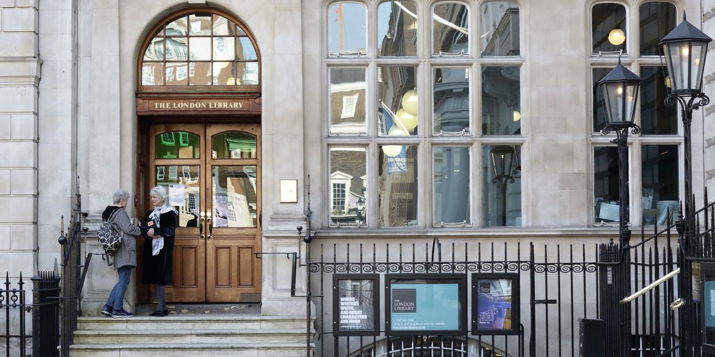 The London Library's stone entrance at number 14, two visitors at the wooden doors.