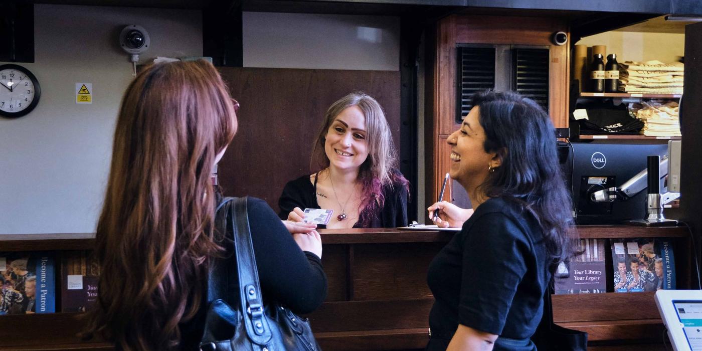 A member is served at the issue desk by two members of staff.