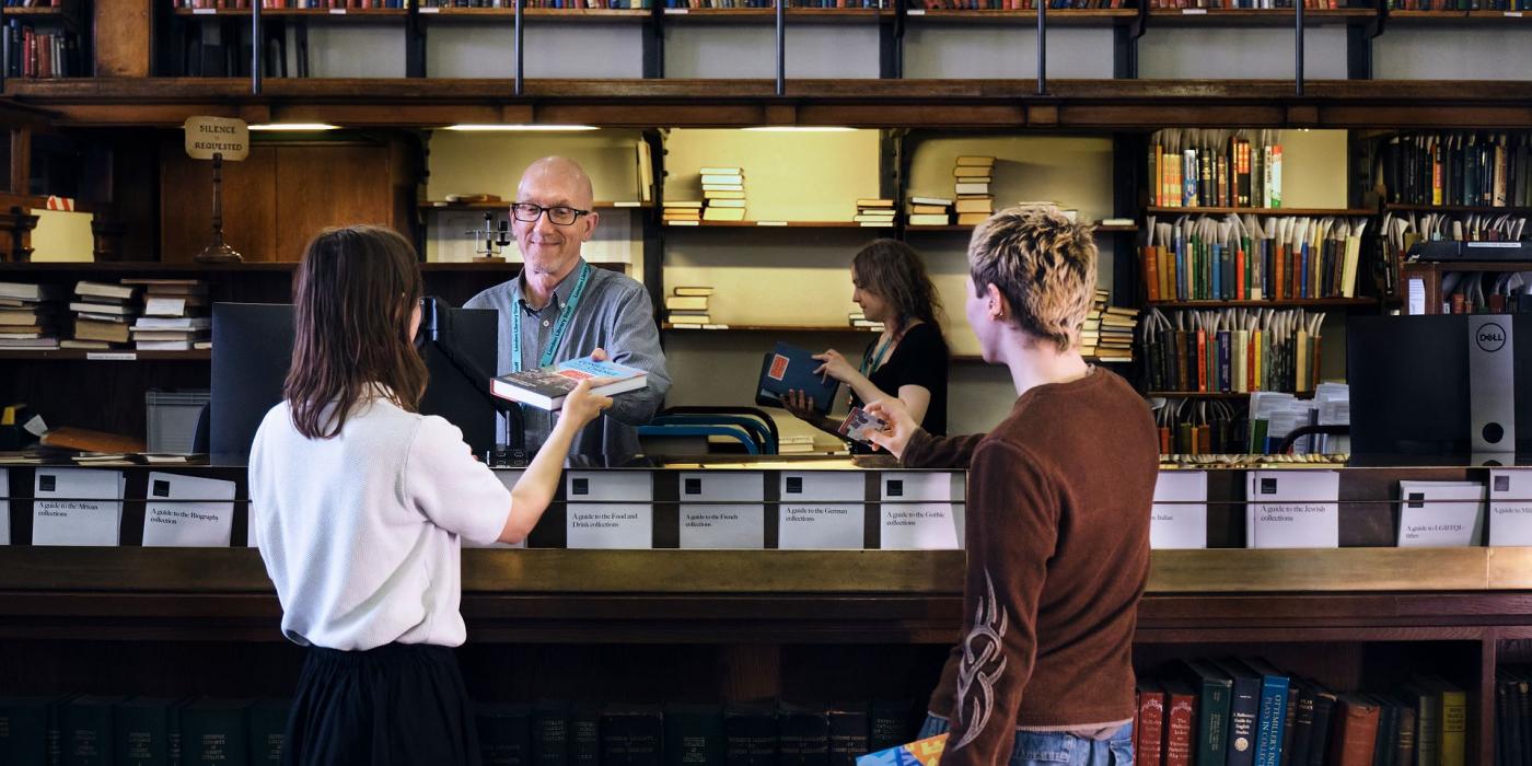Members collecting books at the issue desk, staff serving from behind the counter.