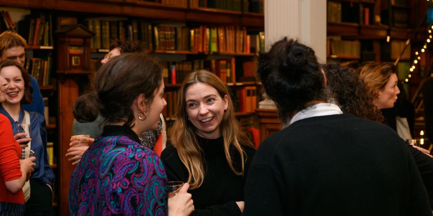 Guests laughing together over glasses of wine at the launch.