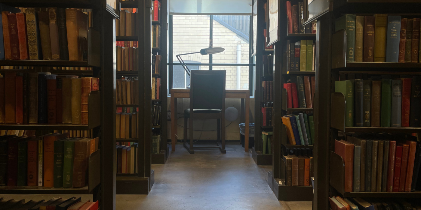 table and chair at the end of a aisle of book shelves