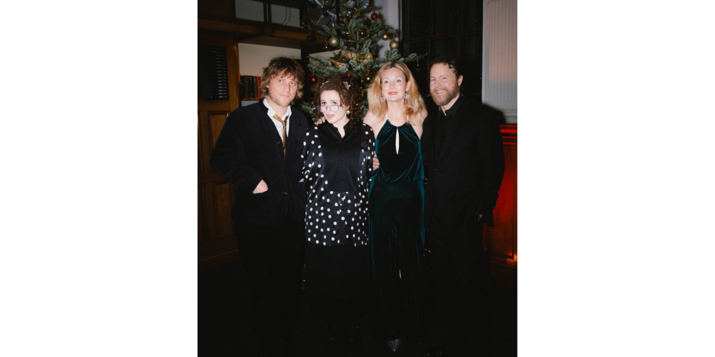 4 people standing in front of a Christmas tree