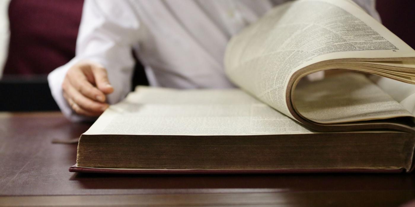 Person turning over page of a big book