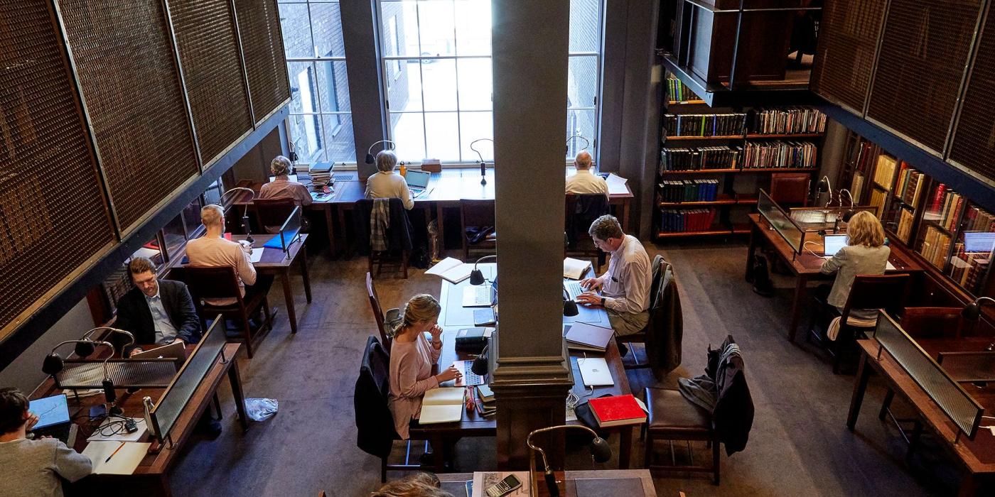 Members at work in the Stoppard Room, lamps and laptops along the timber desks.