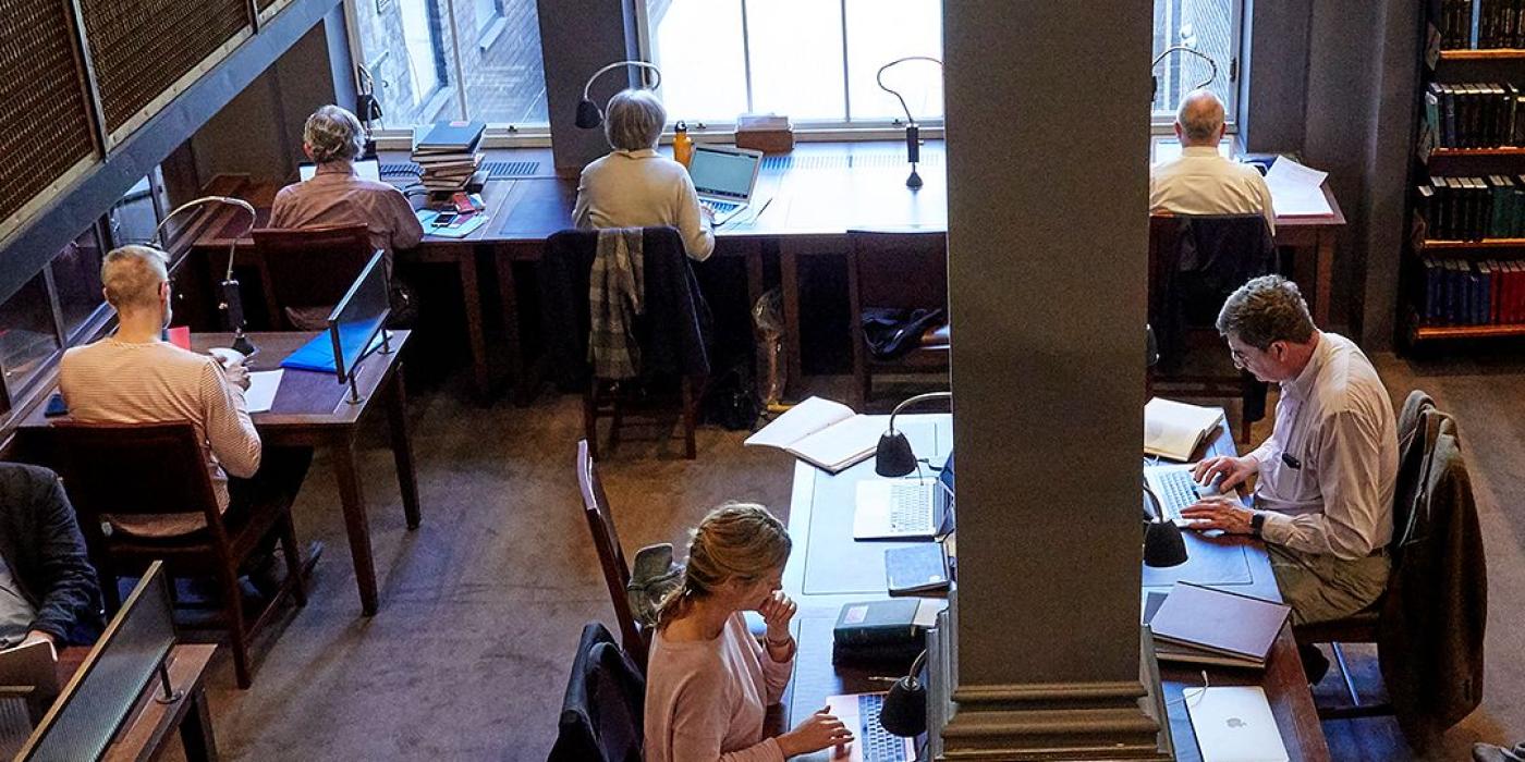 Members at work in the Stoppard Room, lamps and laptops along the timber desks.