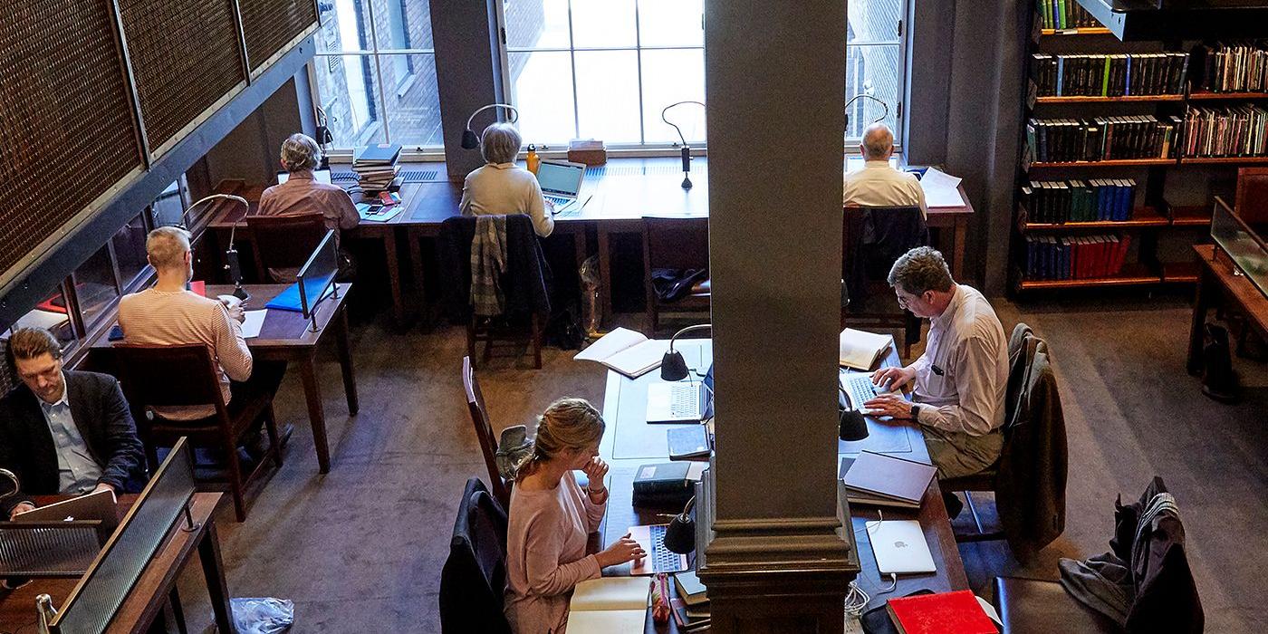 Members at work in the Stoppard Room, lamps and laptops along the timber desks.