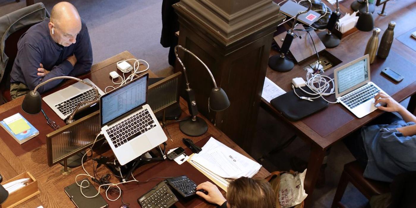 Members working at laptops across the reading room desks, seen from the gallery above.