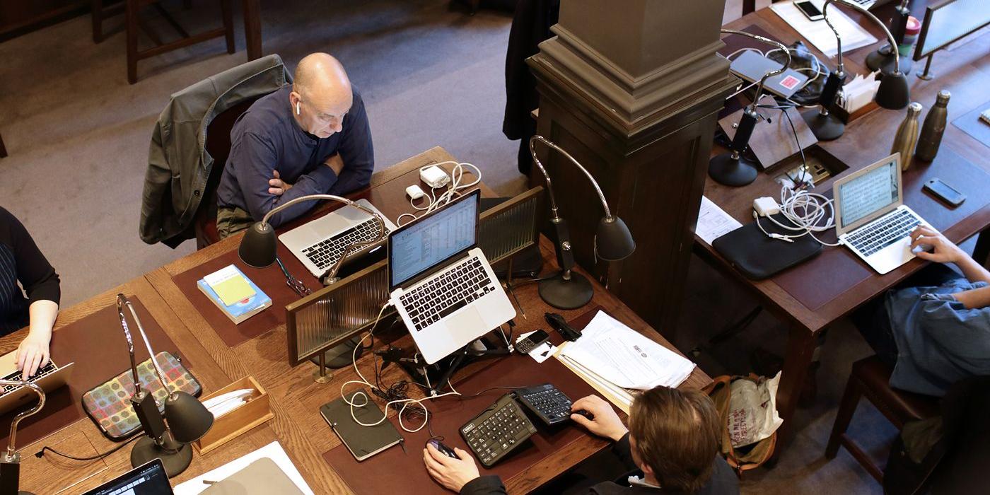Members working at laptops across the reading room desks, seen from the gallery above.