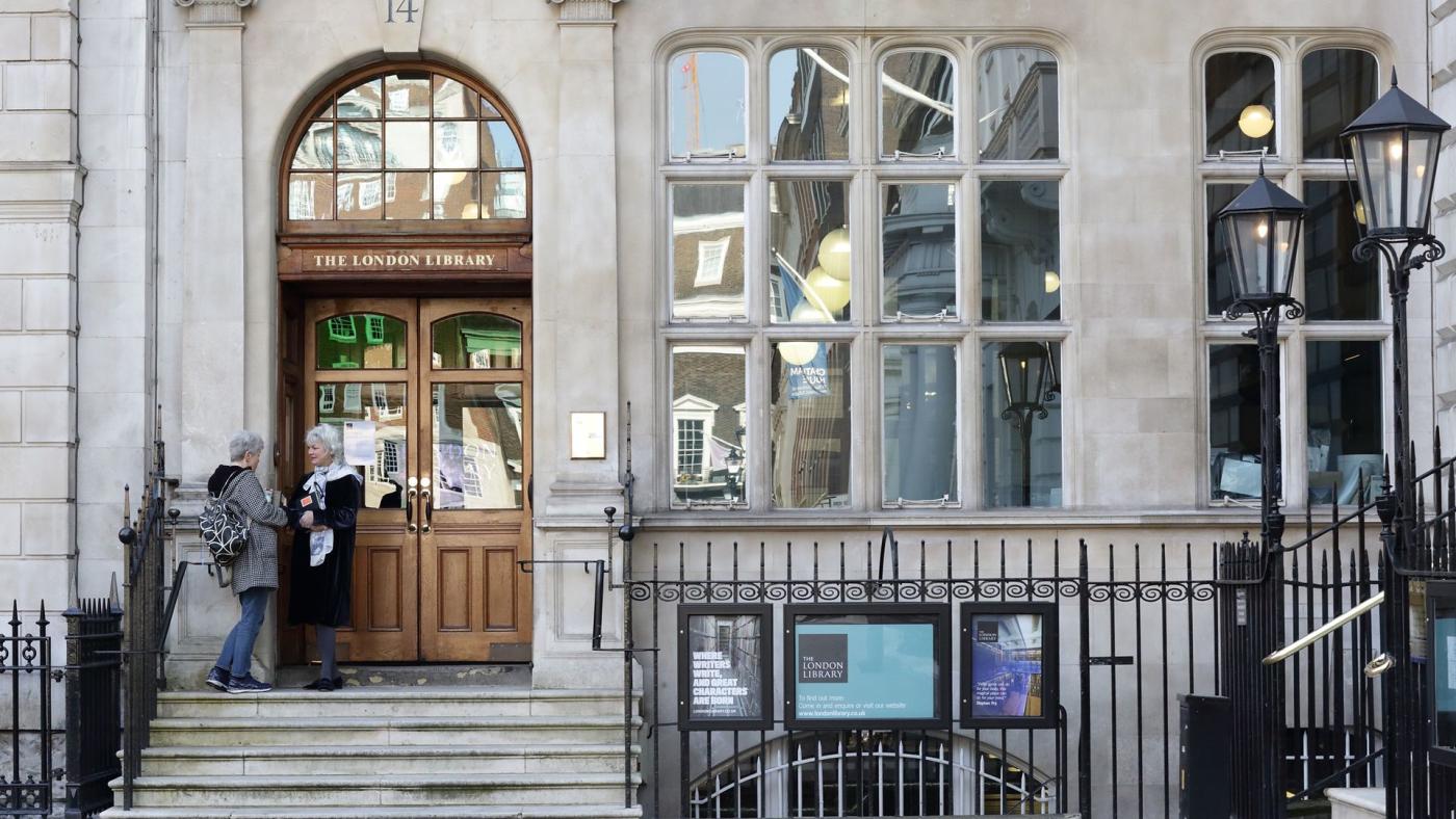 The London Library's stone entrance at number 14, two visitors at the wooden doors.